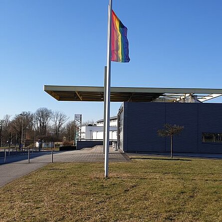 [Translate to Englisch:] gehisste Pride Flagge neben dem Audimax am Campus Zweibrücken