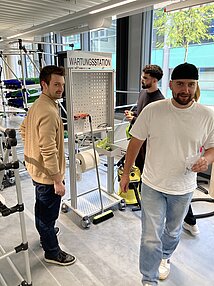 mehrere Studierende stehen rund um eine Reinigungsstation