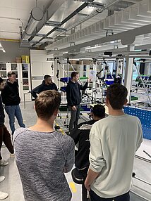 Studierende betrachten die Montagearbeitsplätze