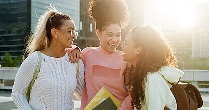 Happy woman, friends and university student with hug, talk and excited for back to school reunion. Girl, group and flare with conversation at college for learning, education and scholarship at campus
